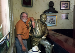 Clay Reynolds posing with a statue of Ernest Hemingway in La Floridita